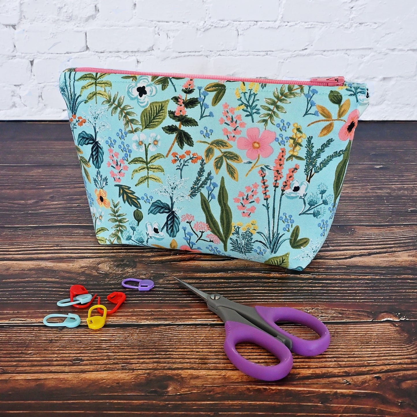 A pretty aqua floral accessory pouch made from a striking cotton from Rifle Paper Co's Amalfi collection. It features a soft coral lining and matching zipper. Great for all your accessories!