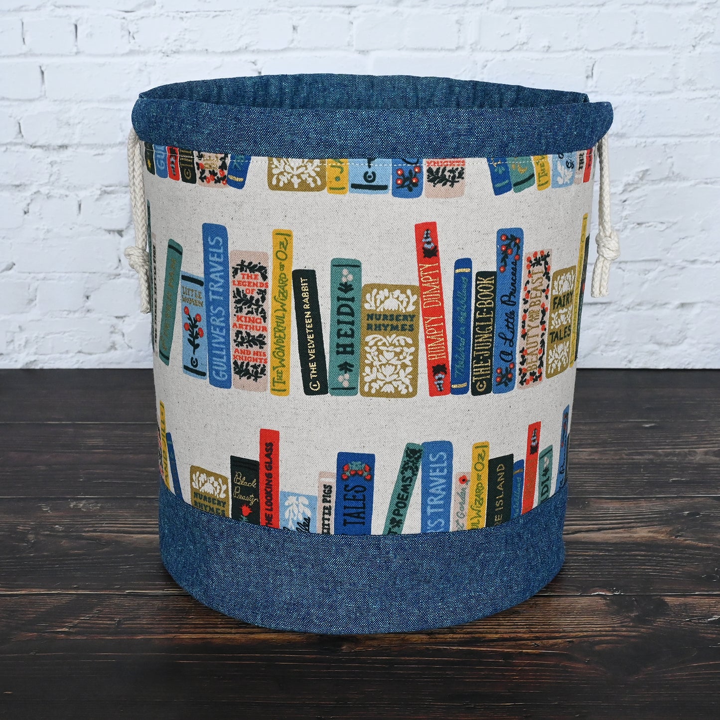 Bucket bag for knitting or crochet made from Rilfe Paper's Book Club Canvas and paired with a peacock linen from Robert Kaufman. Made with multiple pockets and a double drawstring closure. Made in Canada by Yellow Petal Handmade.