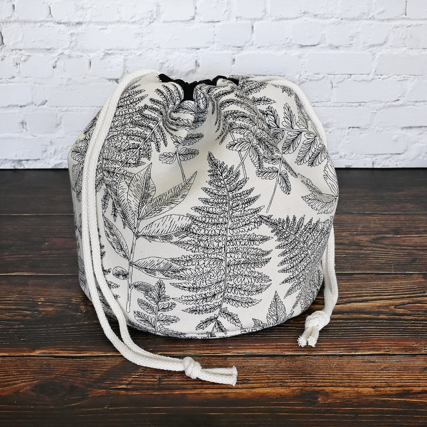 Striking fern pattern bucket bag in cream and black.  Made from the Green Thumb collection by Art Gallery Fabrics, this canvas bucket bag features lots of pockets and a quilted bottom for design and function.  Closes securely with a double drawstring.  Made in Canada by Yellow Petal Handmade.