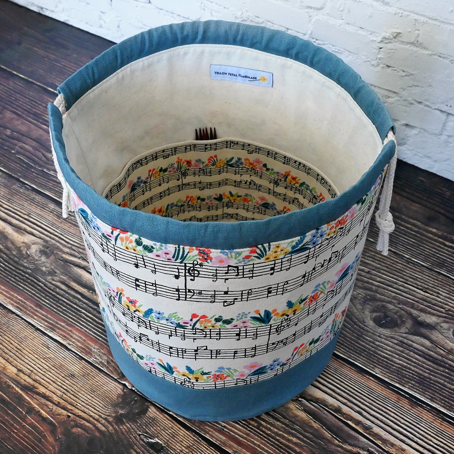 Fun Bucket Bag for knitting and crochet projects.  Features Music Notes Canvas by Rifle Paper Co paired with a steel blue linen.  Equipped with multiple interior pockets and a drawstring closure.  Made in Canada by Yellow Petal Handmade.