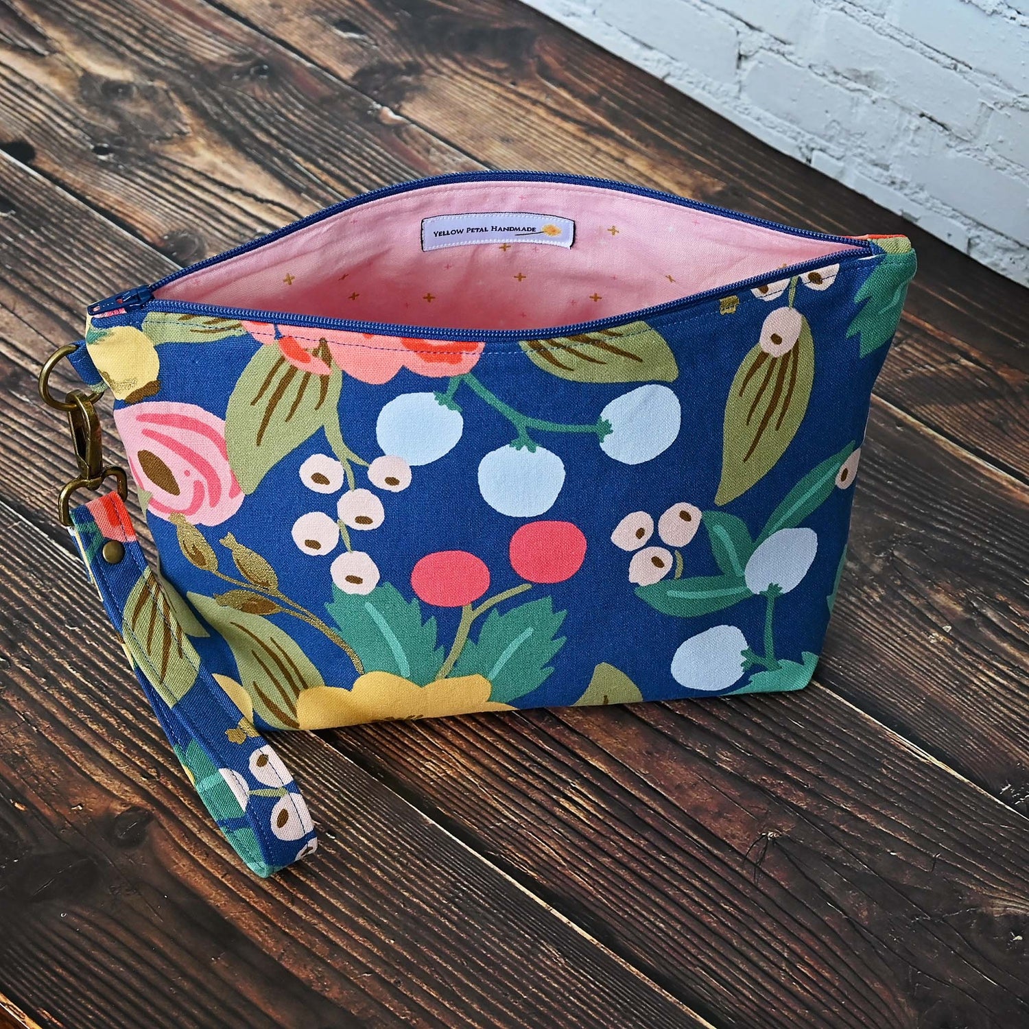 Blue floral canvas zippered pouch with removable wrist strap, lined in a pretty pink cotton.  Made with fabric from Rifle Paper Co and Riley Blake.  Handmade in Canada by Yellow Petal Handmade.