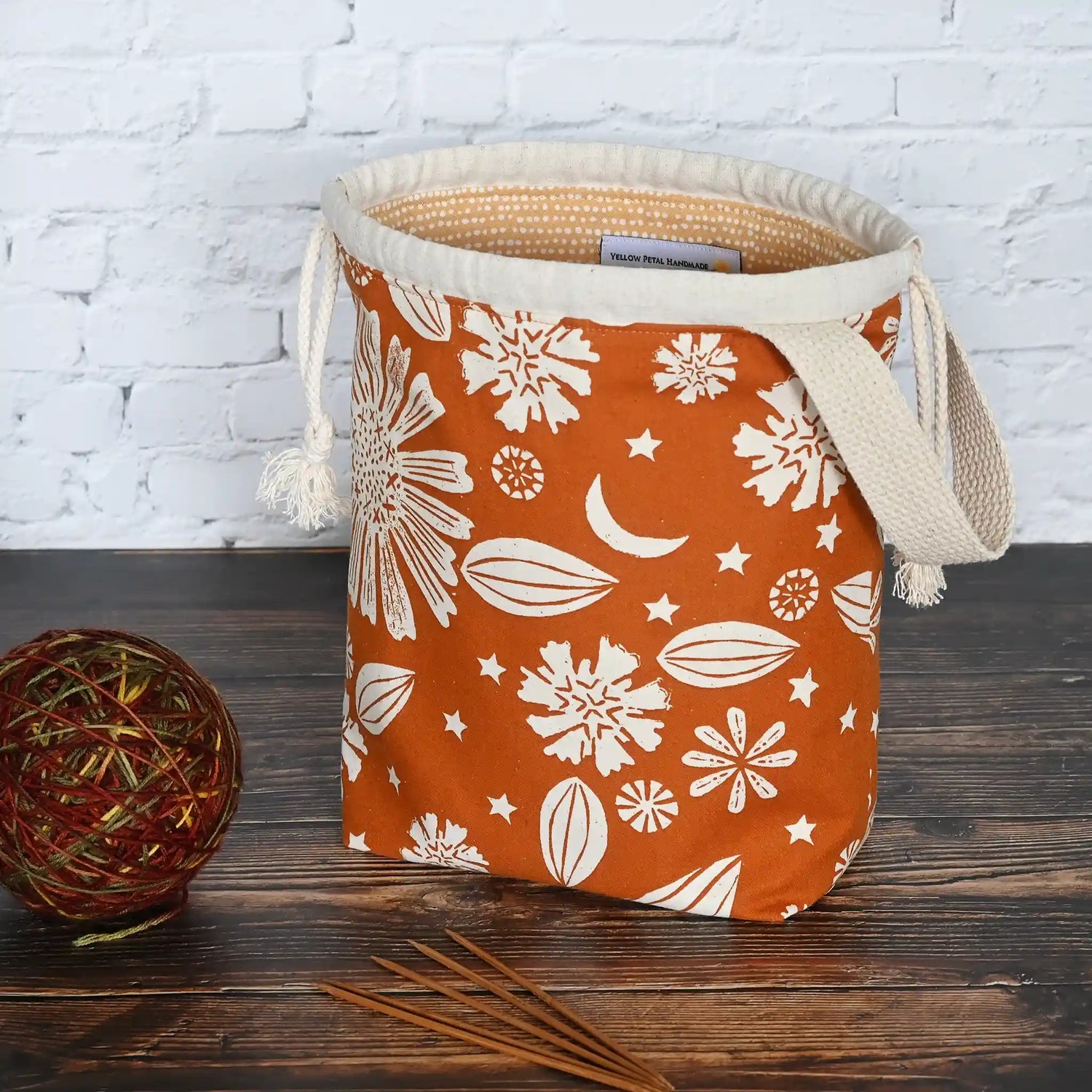 Beautiful drawstring project bag with handle in a burnt orange floral and star fabric and lined in a fun gold dotty cotton.  Handmade in Nova Scotia Canada by Yellow Petal Handmade.