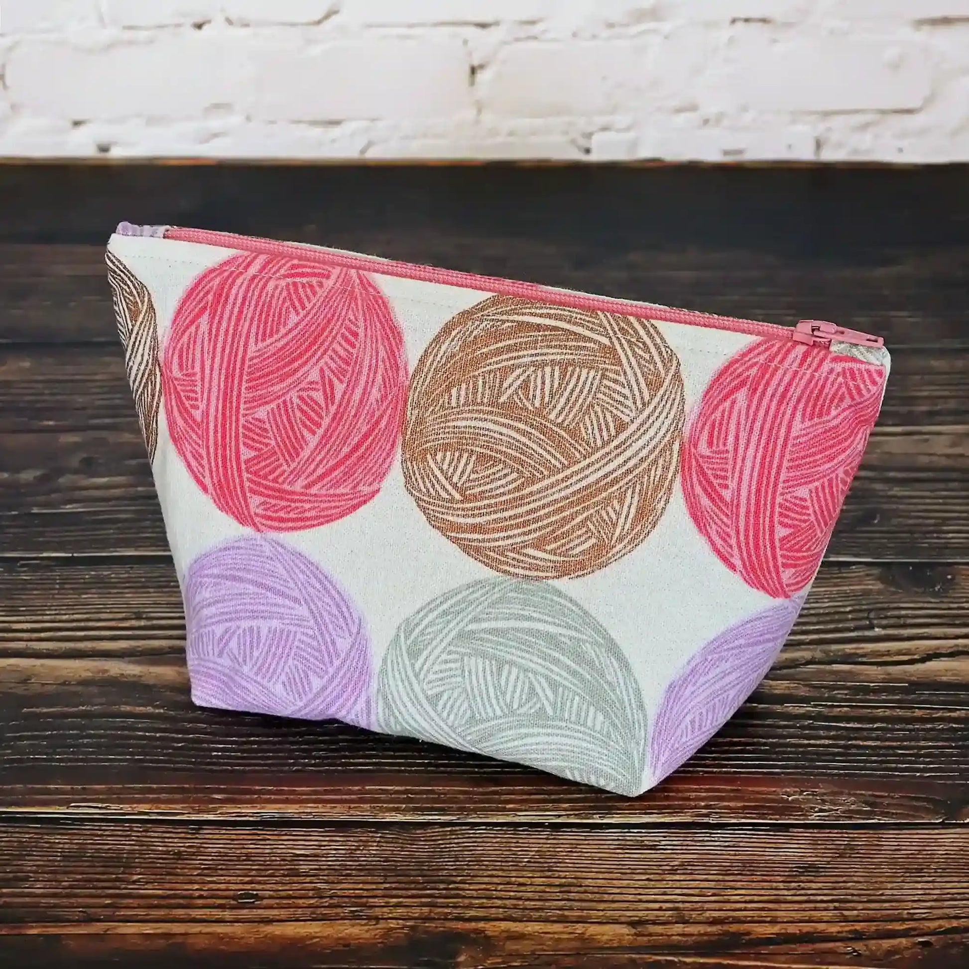 Cute Yarn Balls canvas pouch measuring 8" wide by 5" tall and with a 3.5" boxed bottom.   Fabric has cute yarn balls with metallic copper detailing.  Made in Canada by Yellow Petal Handmade.