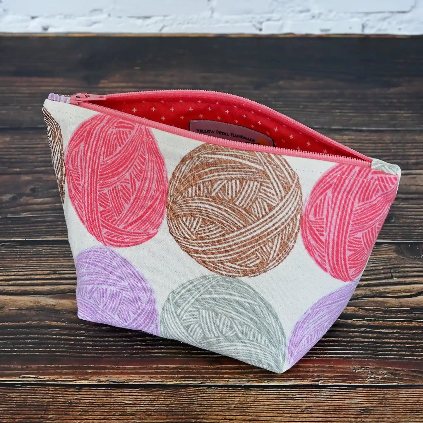 Cute Yarn Balls canvas pouch measuring 8" wide by 5" tall and with a 3.5" boxed bottom.   Fabric has cute yarn balls with metallic copper detailing.  Made in Canada by Yellow Petal Handmade.