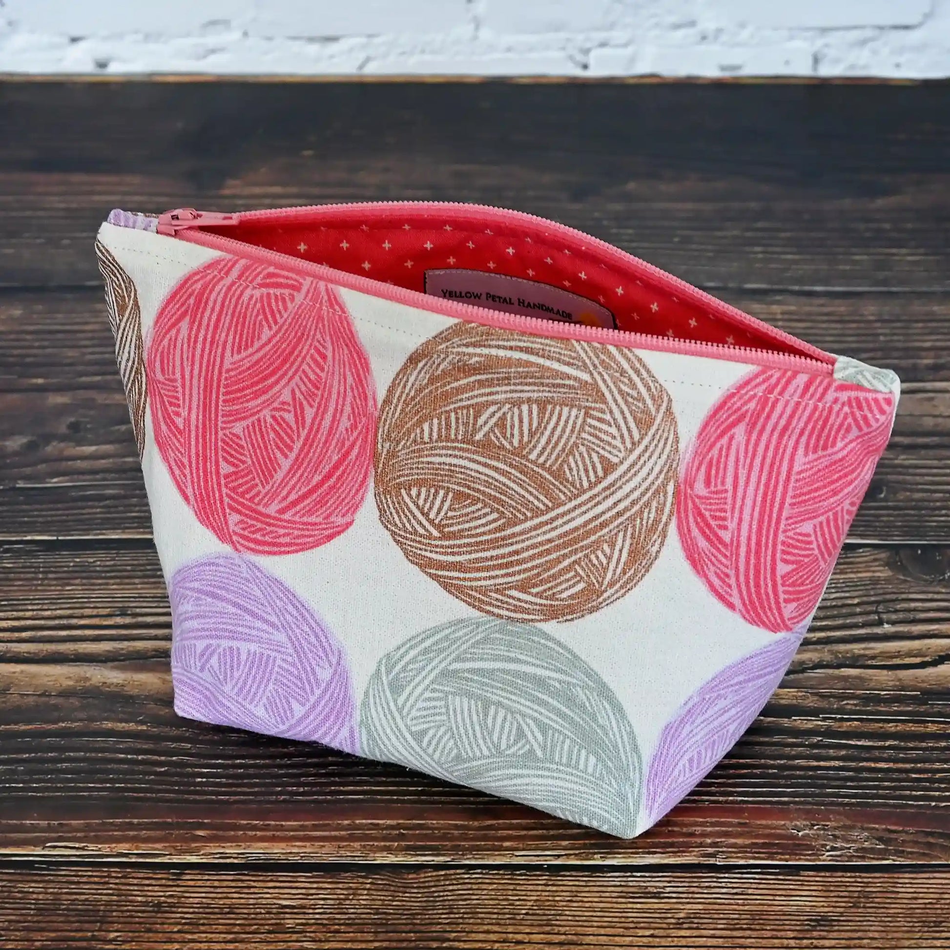 Cute Yarn Balls canvas pouch measuring 8" wide by 5" tall and with a 3.5" boxed bottom.   Fabric has cute yarn balls with metallic copper detailing.  Made in Canada by Yellow Petal Handmade.