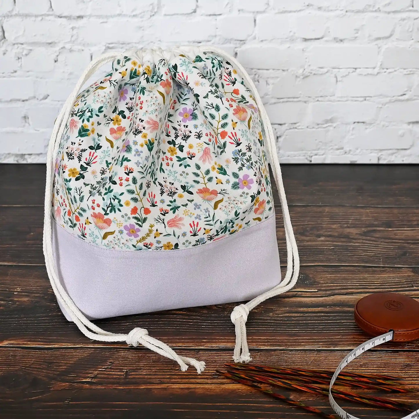 Pretty white floral and mauve linen drawstring project bag in Rifle Paper Co's Curio fabric.  The interior is a pretty mauve fabric with pockets.  Made in Nova Scotia, Canada by Yellow Petal Handmade.