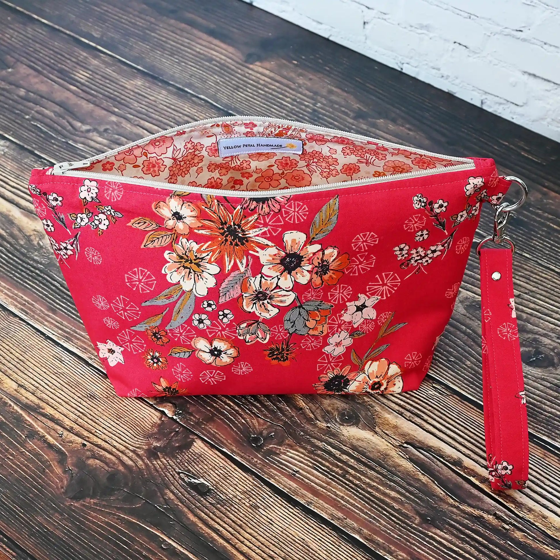 Red floral zippered pouch made from a gorgeous premium cotton from Art Gallery Fabrics.  Lined in a pretty cream and coral paisley floral and comes with a removable wrist strap.  Made in Canada by Yellow Petal Handmade.